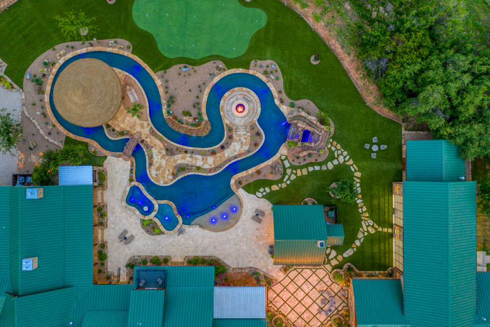 Esempio di un'ampia piscina rustica personalizzata dietro casa con un acquascivolo e pavimentazioni in pietra naturale