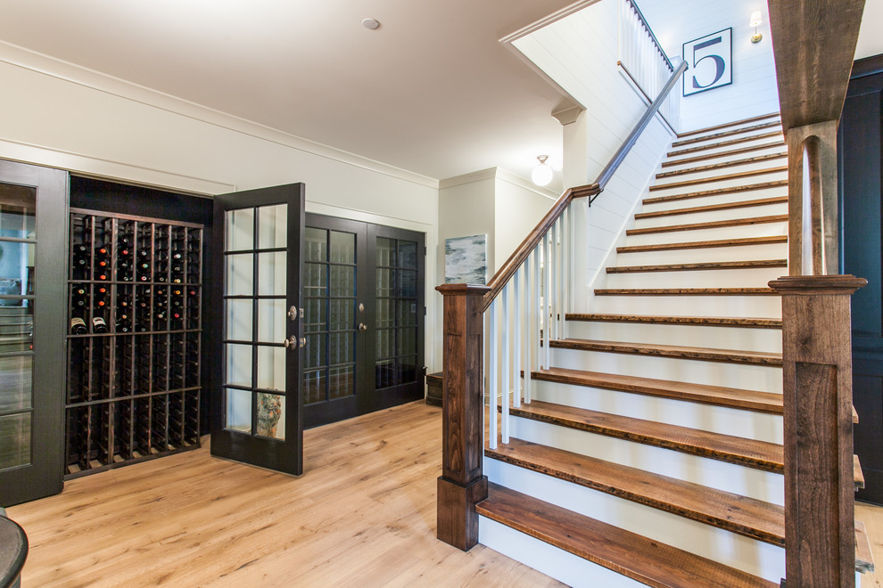 This is an example of an eclectic wine cellar with light hardwood floors, storage racks and beige floor.