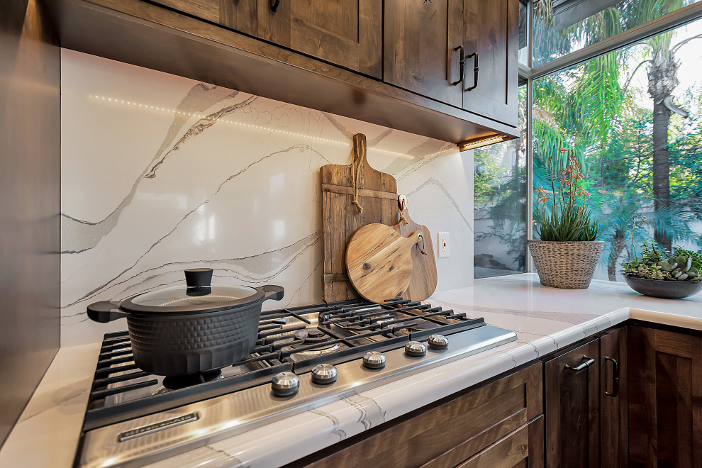 Example of a large transitional u-shaped open concept kitchen design in Phoenix with a farmhouse sink, shaker cabinets, dark wood cabinets, quartz countertops, white backsplash, quartz backsplash, stainless steel appliances, an island and white countertops