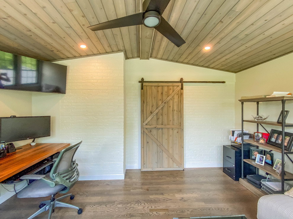 Aménagement d'un bureau de taille moyenne avec un mur beige, sol en stratifié, un bureau indépendant, un sol marron et un plafond voûté.