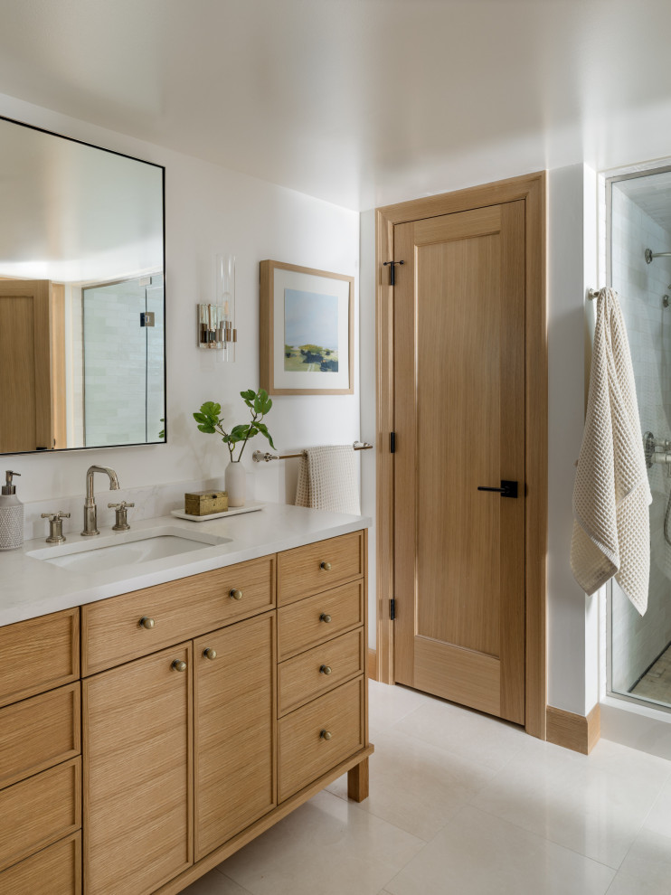 Mid-sized transitional master white tile white floor and single-sink alcove shower photo in Seattle with recessed-panel cabinets, brown cabinets, an undermount sink, quartz countertops, a hinged shower door, white countertops and a freestanding vanity