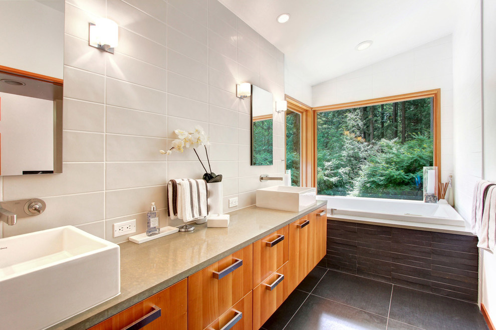 Large contemporary master bathroom in Seattle with flat-panel cabinets, medium wood cabinets, a drop-in tub, gray tile, porcelain tile, white walls, porcelain floors, a vessel sink and concrete benchtops.