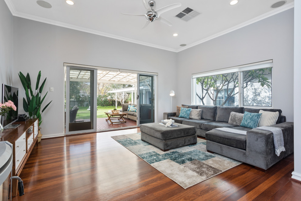 Large contemporary living room in Perth with grey walls, brown floor, medium hardwood floors and a freestanding tv.