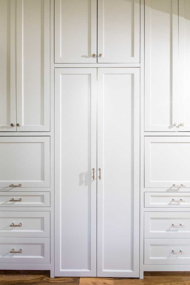 Design ideas for a mid-sized transitional kitchen pantry in Atlanta with a farmhouse sink, beaded inset cabinets, white cabinets, quartz benchtops, white splashback, porcelain splashback, panelled appliances, light hardwood floors, with island, brown floor and white benchtop.