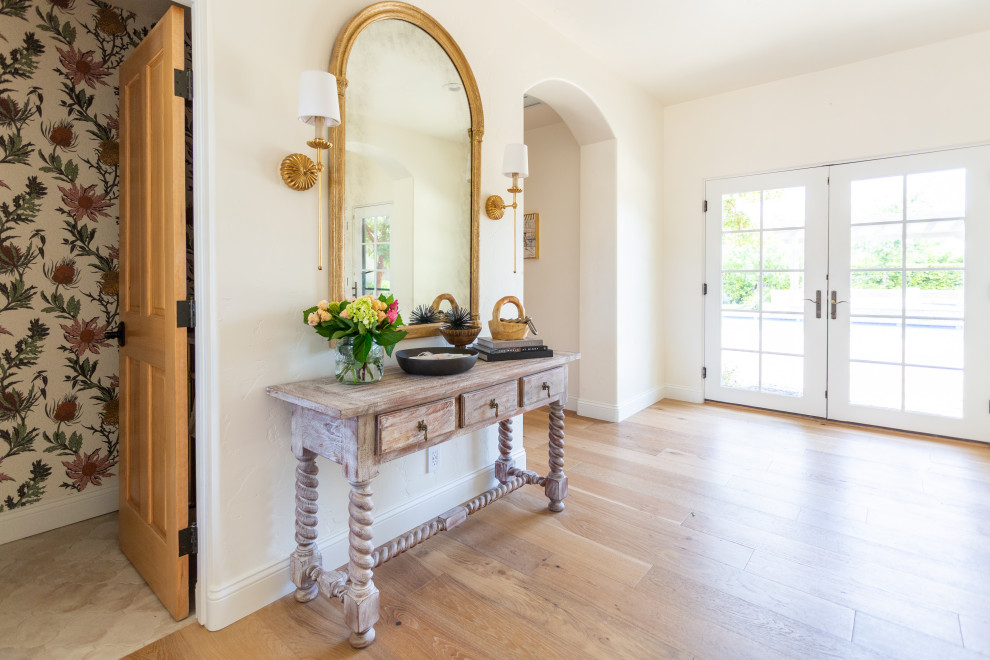 Photo of a large entryway in Santa Barbara with white walls, light hardwood floors and beige floor.