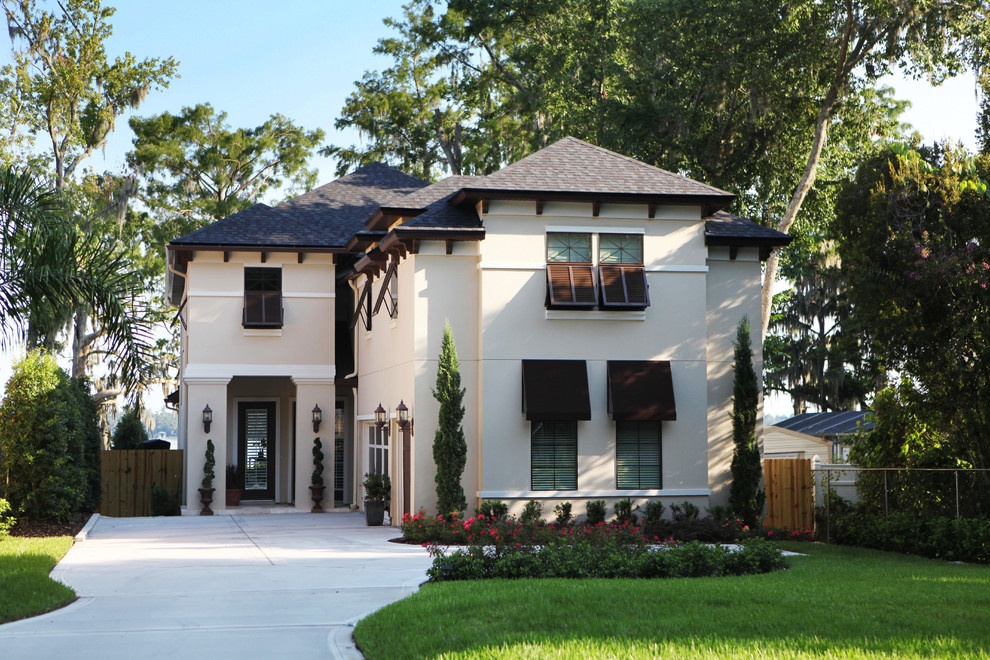 This is an example of a mid-sized mediterranean two-storey stucco beige house exterior in Jacksonville with a gable roof and a shingle roof.