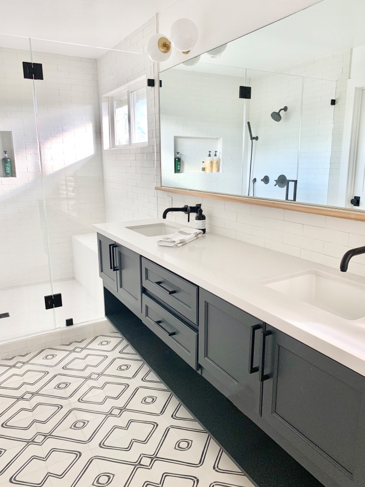 This is an example of a mid-sized eclectic master bathroom in San Francisco with recessed-panel cabinets, black cabinets, a double shower, a one-piece toilet, white tile, ceramic tile, white walls, cement tiles, an undermount sink, engineered quartz benchtops, black floor, a hinged shower door, white benchtops, a shower seat, a double vanity and a floating vanity.