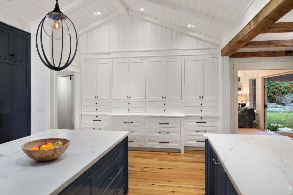 Modern inredning av ett stort vit vitt u-kök, med en rustik diskho, luckor med infälld panel, blå skåp, marmorbänkskiva, vitt stänkskydd, stänkskydd i terrakottakakel, rostfria vitvaror, ljust trägolv och en köksö