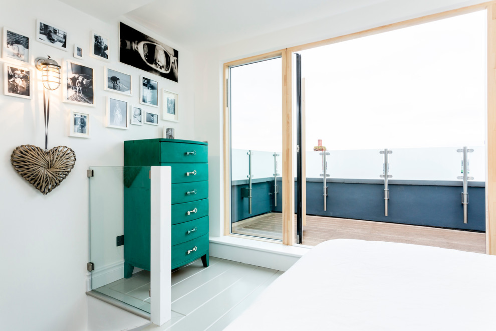 This is an example of a beach style master bedroom in Hampshire with painted wood floors.