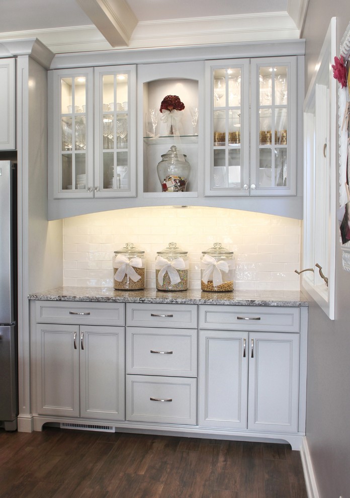 Inspiration for a large transitional l-shaped porcelain tile kitchen pantry remodel with shaker cabinets, gray cabinets, granite countertops, white backsplash, glass tile backsplash and an island