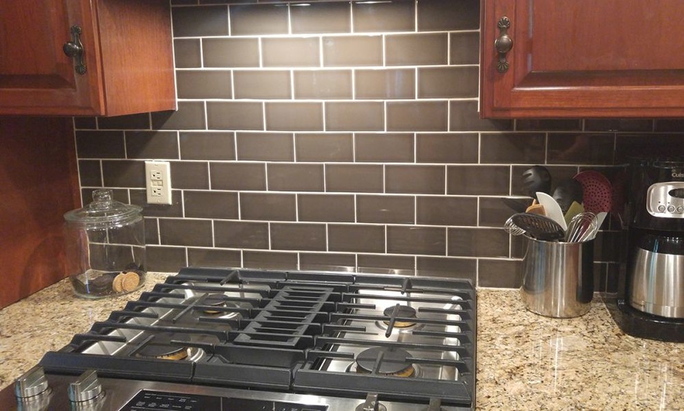 Example of a mid-sized transitional l-shaped ceramic tile kitchen design with raised-panel cabinets, dark wood cabinets, granite countertops, brown backsplash, subway tile backsplash, stainless steel appliances and an island