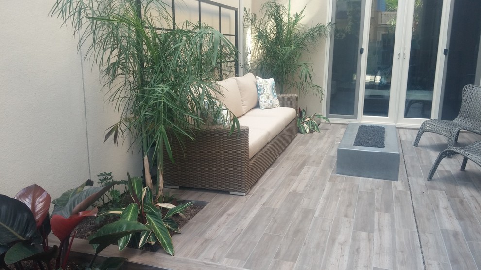 This is an example of a small contemporary courtyard deck in Orange County with a fire feature.