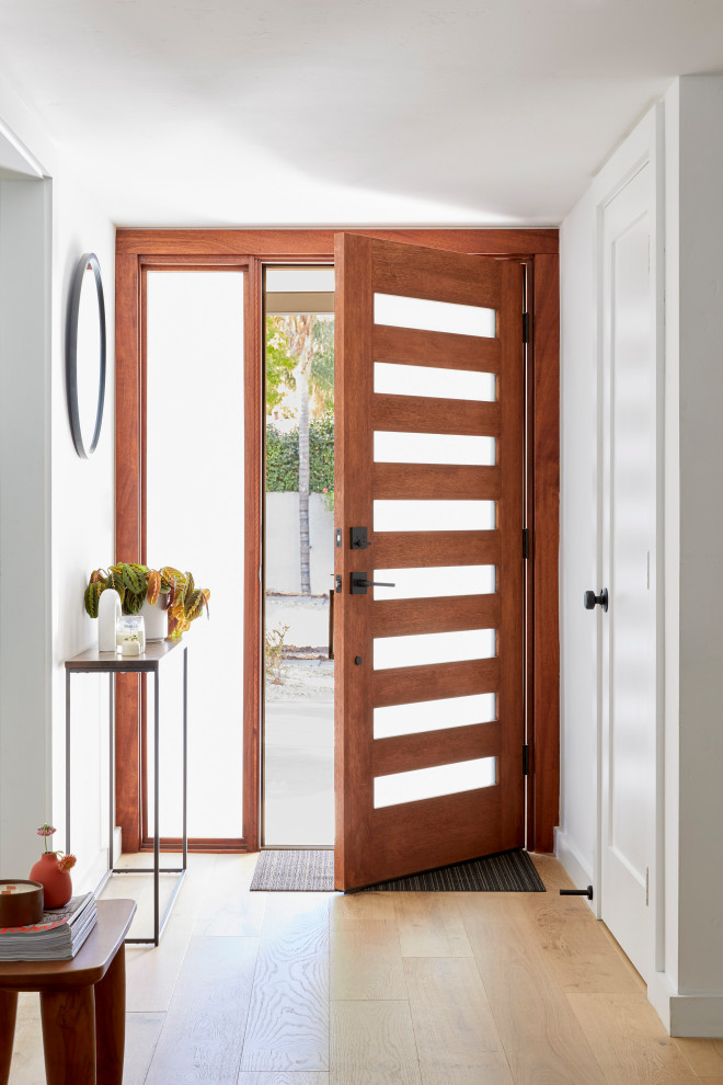 Aménagement d'une petite porte d'entrée rétro avec un mur blanc, parquet clair, une porte simple, une porte en bois brun et un sol marron.
