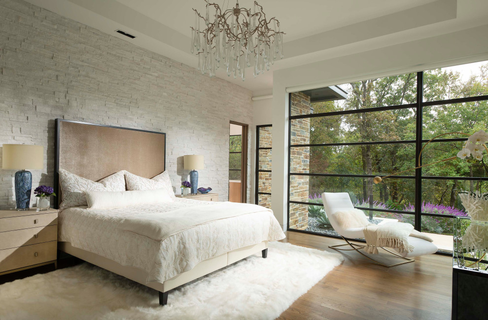 This is an example of a mid-sized contemporary master bedroom in Dallas with white walls, medium hardwood floors, no fireplace, brown floor and brick walls.