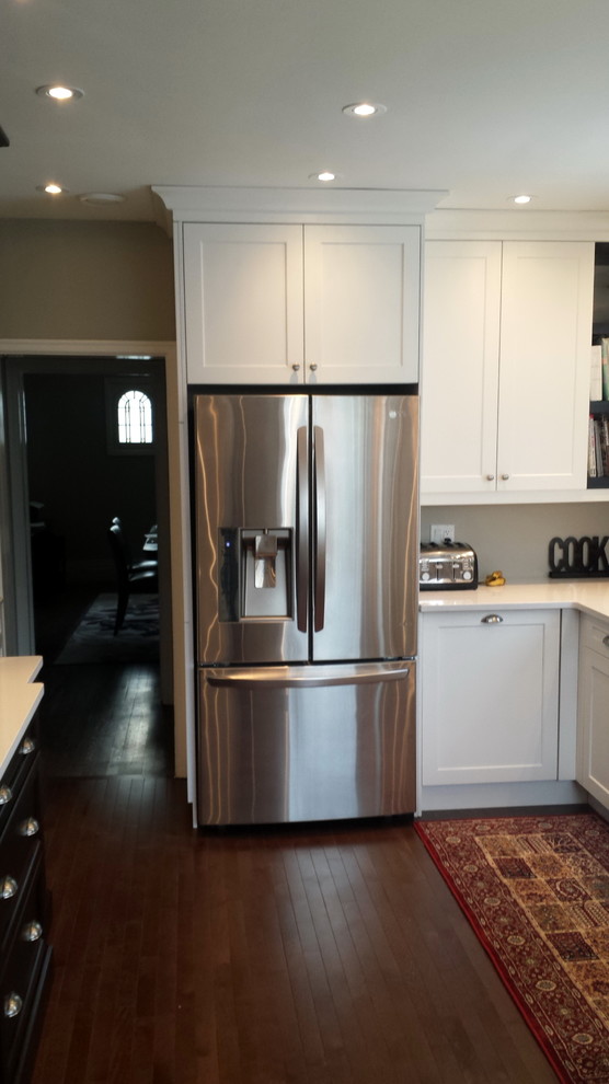 Example of a mid-sized transitional u-shaped dark wood floor enclosed kitchen design in Ottawa with an undermount sink, shaker cabinets, white cabinets, quartz countertops, white backsplash, subway tile backsplash, stainless steel appliances and a peninsula