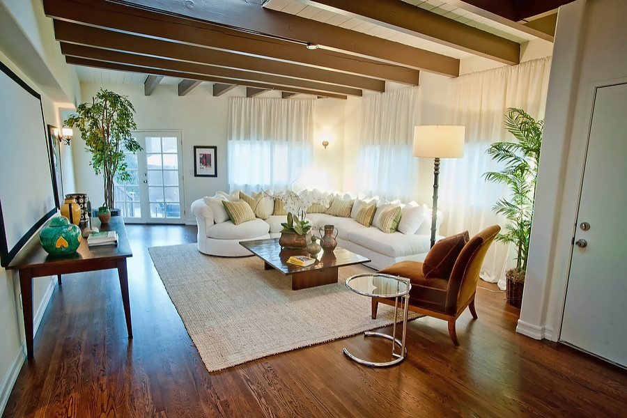 This is an example of a transitional enclosed family room in Los Angeles with white walls, dark hardwood floors and brown floor.