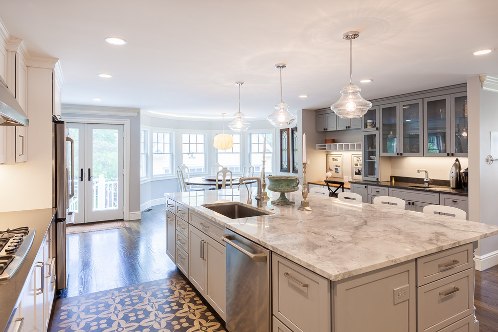 Photo of a large traditional u-shaped kitchen in Boston with a single-bowl sink, shaker cabinets, granite benchtops, grey splashback, porcelain splashback, stainless steel appliances, dark hardwood floors, with island and grey cabinets.