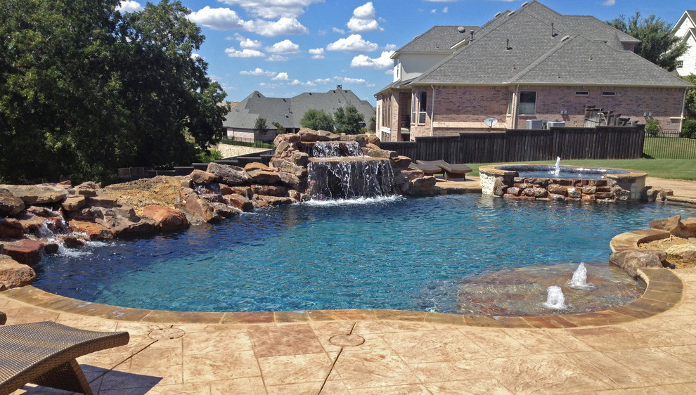 Photo of a mid-sized backyard custom-shaped natural pool in Dallas with a hot tub and natural stone pavers.