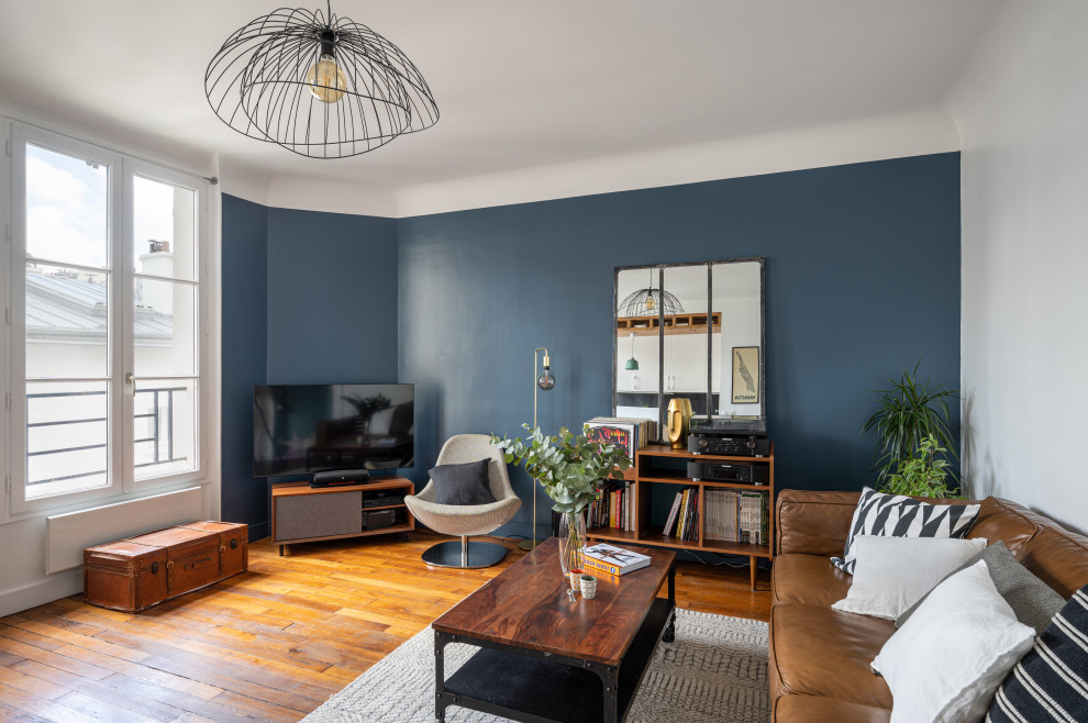 На фото: открытая гостиная комната среднего размера в современном стиле с музыкальной комнатой, синими стенами, паркетным полом среднего тона и телевизором в углу
