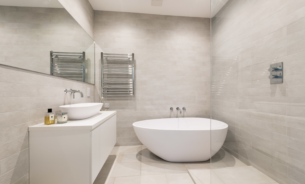 Inspiration for a contemporary master wet room bathroom in London with flat-panel cabinets, white cabinets, a freestanding tub, gray tile, grey walls, a vessel sink, beige floor, an open shower and white benchtops.