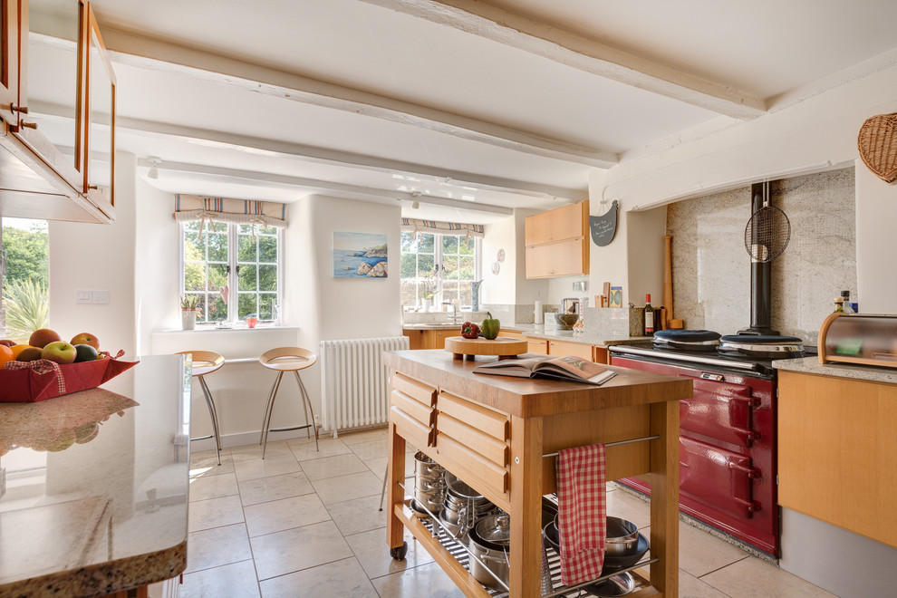 Photo of a mid-sized country kitchen in Devon with flat-panel cabinets, medium wood cabinets, granite benchtops, beige splashback, ceramic splashback, coloured appliances, ceramic floors and with island.