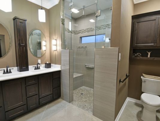Large transitional master multicolored tile and stone tile ceramic tile and beige floor walk-in shower photo in Miami with shaker cabinets, dark wood cabinets, a one-piece toilet, beige walls, an undermount sink, solid surface countertops and a hinged shower door