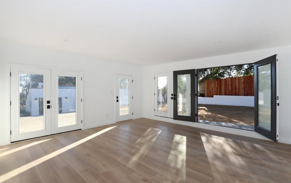 Expansive mediterranean master bedroom in Los Angeles with white walls, light hardwood floors and brown floor.
