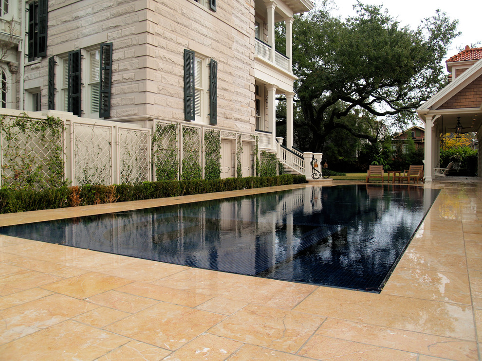 This is an example of a mid-sized mediterranean backyard custom-shaped infinity pool in New Orleans with natural stone pavers and a pool house.