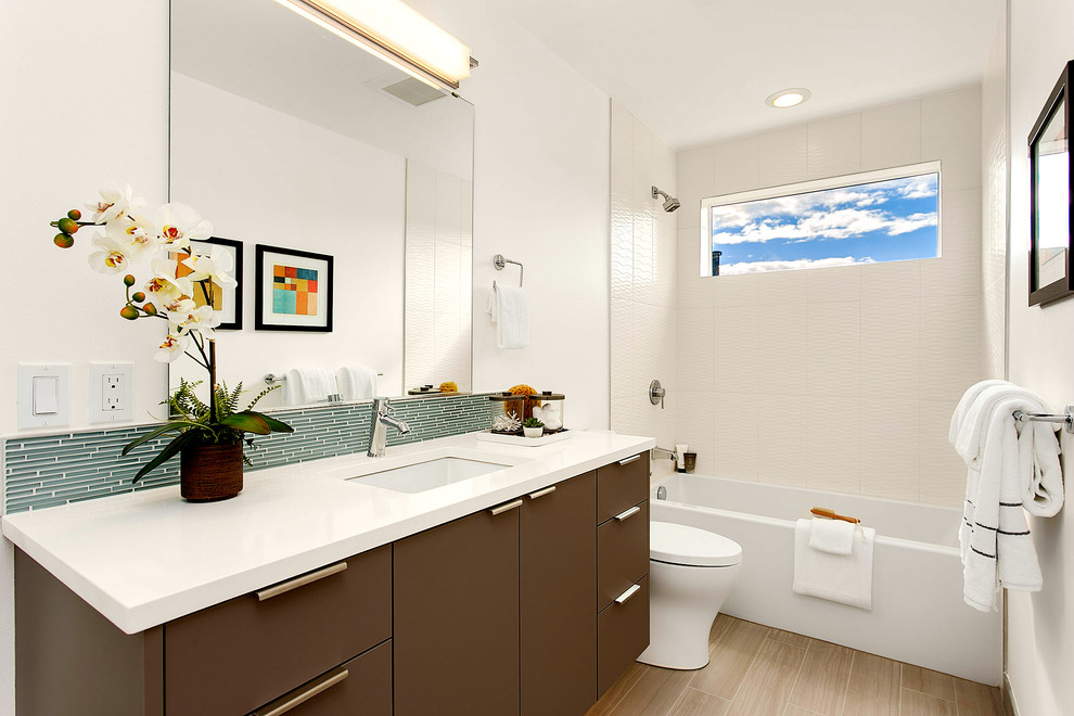 Mid-sized contemporary 3/4 bathroom in Seattle with flat-panel cabinets, brown cabinets, a drop-in tub, a shower/bathtub combo, a two-piece toilet, green tile, matchstick tile, white walls, light hardwood floors, an undermount sink and solid surface benchtops.