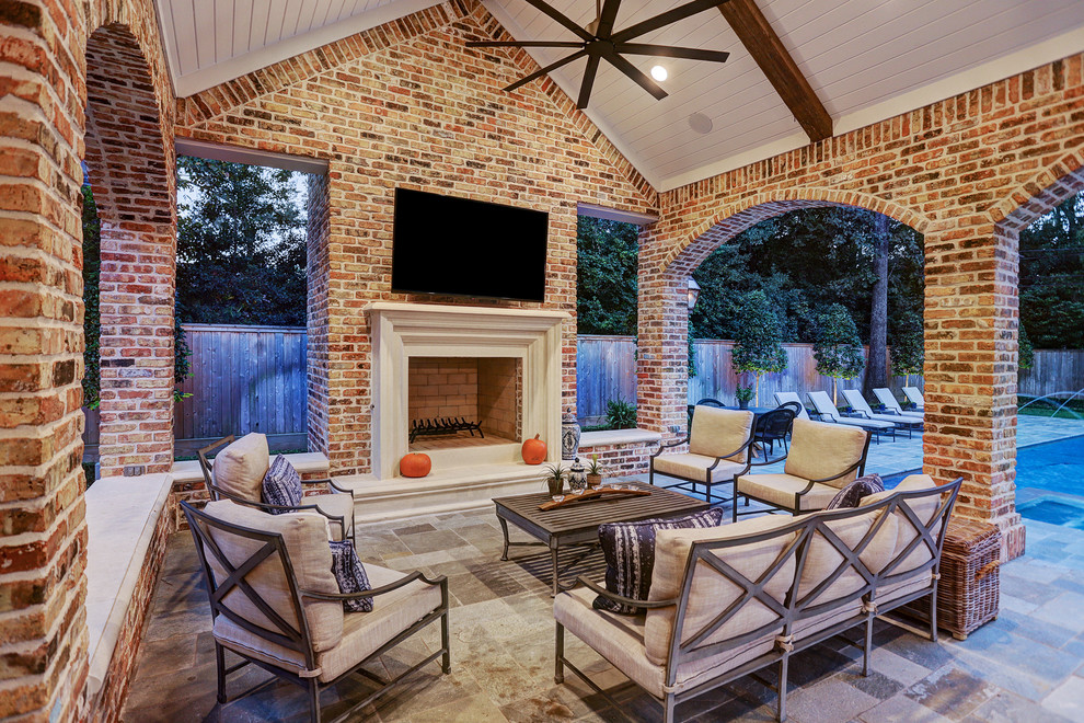 Design ideas for a mid-sized traditional backyard patio in Houston with an outdoor kitchen, natural stone pavers and a roof extension.