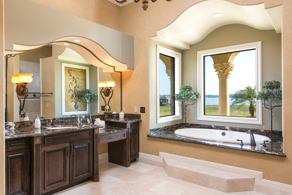Design ideas for an expansive mediterranean master bathroom in Orlando with an integrated sink, beaded inset cabinets, dark wood cabinets, granite benchtops, a hot tub, a corner shower, a two-piece toilet, brown tile, glass tile, beige walls and travertine floors.