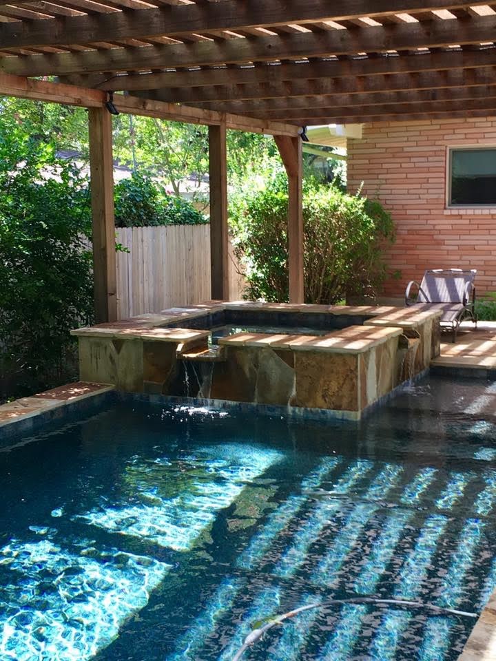 This is an example of a mid-sized tropical backyard custom-shaped lap pool in Austin with a hot tub and natural stone pavers.