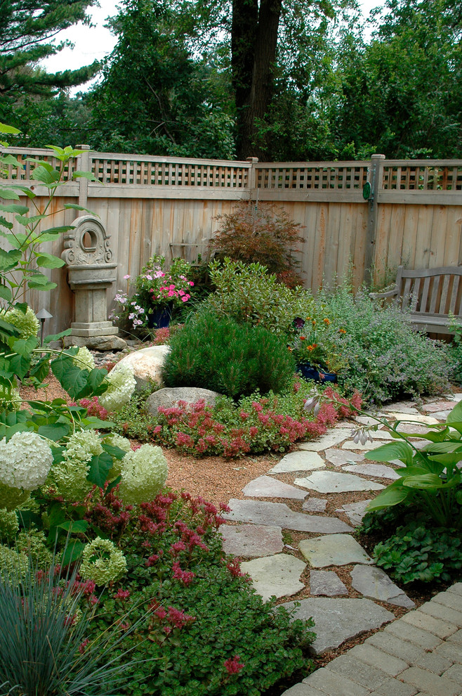 This is an example of a traditional backyard garden in Chicago with natural stone pavers.