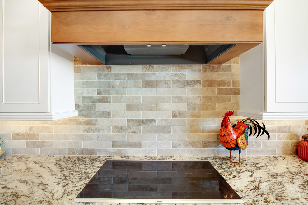 Example of a large transitional u-shaped travertine floor and beige floor open concept kitchen design in Phoenix with a farmhouse sink, recessed-panel cabinets, white cabinets, granite countertops, gray backsplash, porcelain backsplash, stainless steel appliances, an island and multicolored countertops