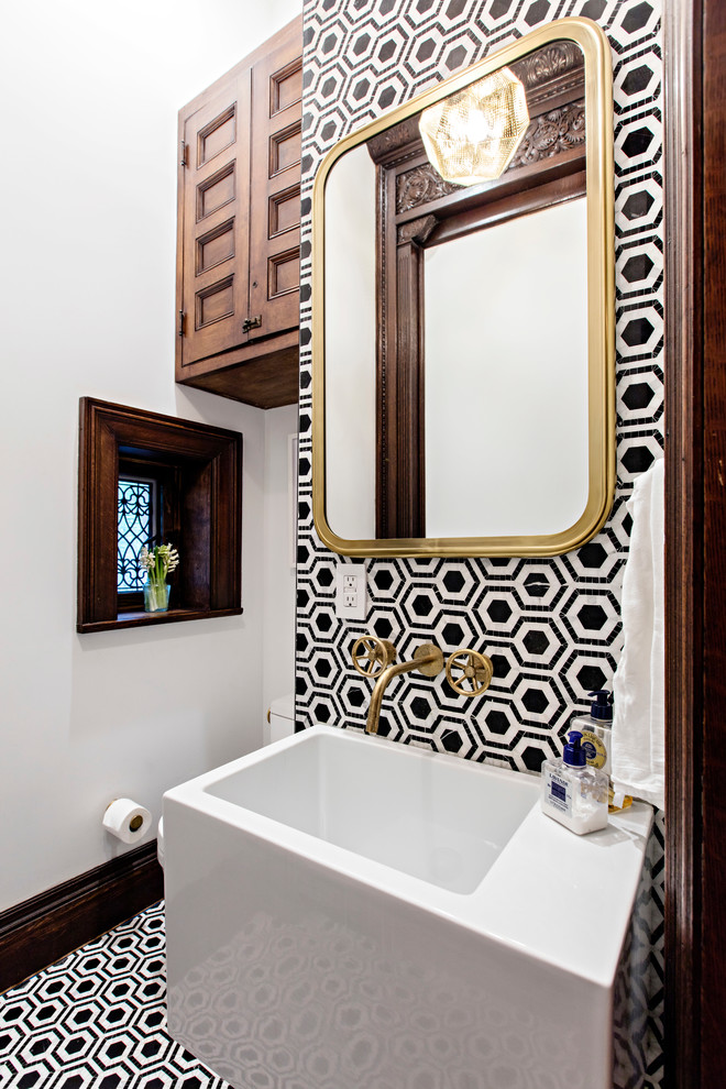 This is an example of a mid-sized eclectic powder room in New York with dark wood cabinets, a two-piece toilet, black and white tile, white walls, a wall-mount sink and marble benchtops.