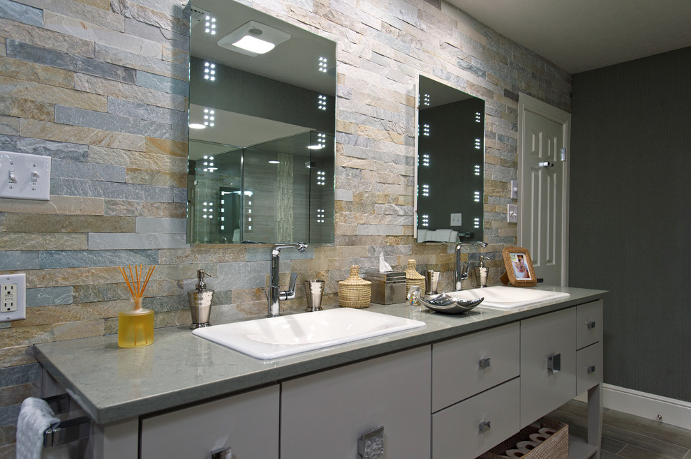 Design ideas for a large contemporary master bathroom in Austin with a drop-in sink, flat-panel cabinets, grey cabinets, solid surface benchtops, a drop-in tub, a corner shower, a two-piece toilet, gray tile, porcelain tile, grey walls and porcelain floors.