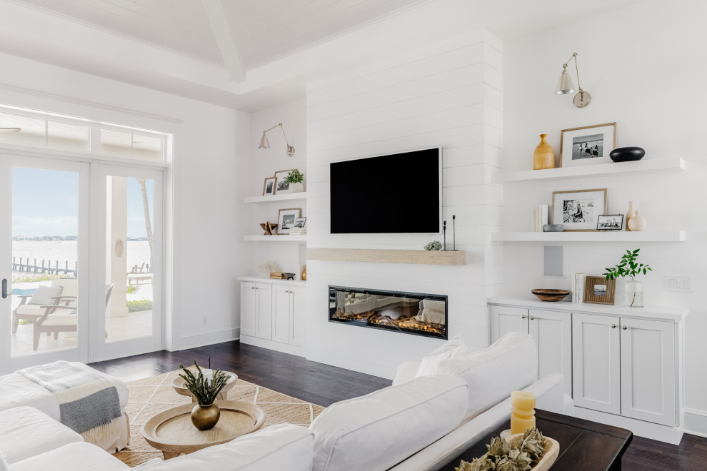 Inspiration for a large nautical open plan living room in Miami with white walls, dark hardwood flooring, a standard fireplace, a timber clad chimney breast, a built-in media unit, brown floors and a drop ceiling.