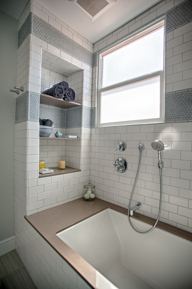 Photo of a country master bathroom in San Francisco with flat-panel cabinets, white cabinets, an alcove tub, a shower/bathtub combo, a one-piece toilet, white tile, subway tile, white walls, vinyl floors, an undermount sink and solid surface benchtops.