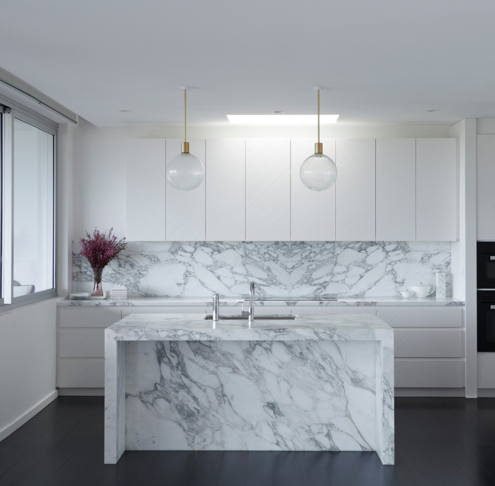 Inspiration for a mid-sized contemporary galley kitchen in London with an undermount sink, flat-panel cabinets, white cabinets, grey splashback, dark hardwood floors, with island, brown floor and grey benchtop.