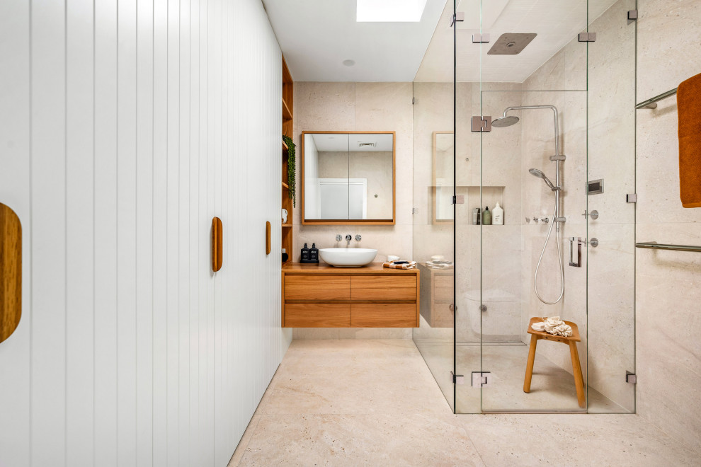 Large beach style master bathroom in Newcastle - Maitland with flat-panel cabinets, medium wood cabinets, a corner shower, a one-piece toilet, beige tile, a vessel sink, wood benchtops, beige floor, a hinged shower door, a single vanity and a floating vanity.