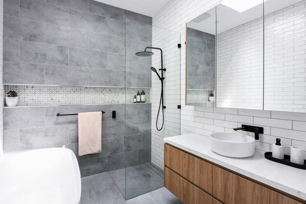 Design ideas for a mid-sized contemporary master bathroom in Sydney with flat-panel cabinets, medium wood cabinets, a freestanding tub, an open shower, a one-piece toilet, white tile, ceramic tile, white walls, ceramic floors, a drop-in sink, engineered quartz benchtops, grey floor, an open shower, white benchtops, a niche, a single vanity and a floating vanity.