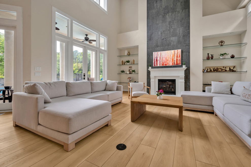 Inspiration for a large modern formal open concept living room in Raleigh with beige walls, vinyl floors, a standard fireplace, a concrete fireplace surround, a wall-mounted tv, beige floor and vaulted.