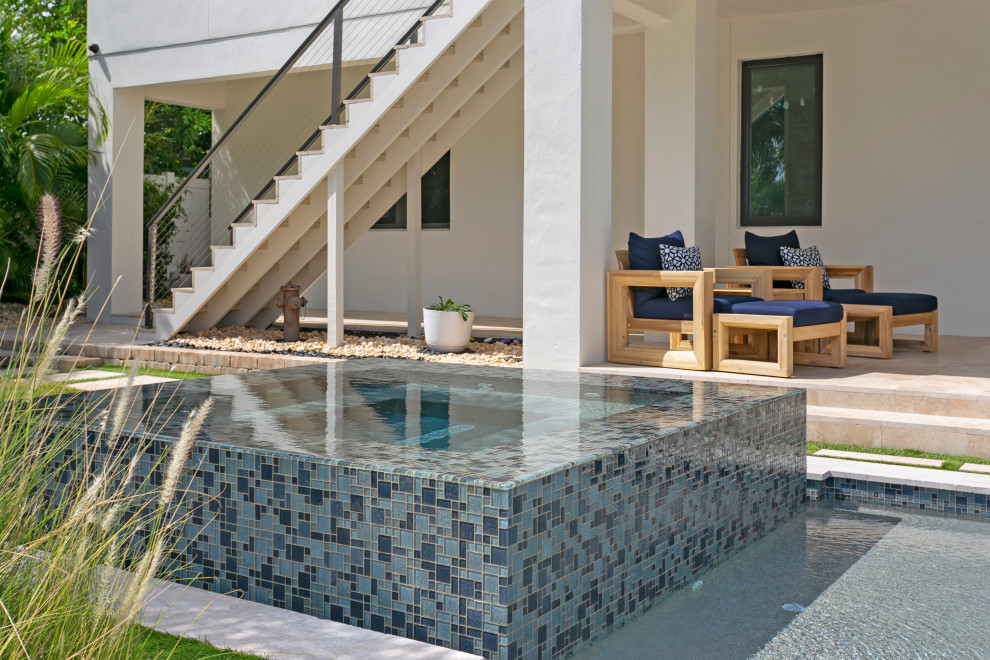 Идея дизайна: прямоугольный бассейн-инфинити среднего размера на заднем дворе в современном стиле с джакузи и покрытием из каменной брусчатки
