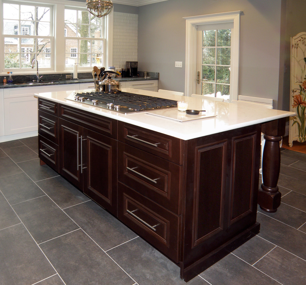 Enclosed kitchen - large transitional l-shaped ceramic tile enclosed kitchen idea in Baltimore with an undermount sink, raised-panel cabinets, dark wood cabinets, soapstone countertops, green backsplash, glass tile backsplash, stainless steel appliances and an island