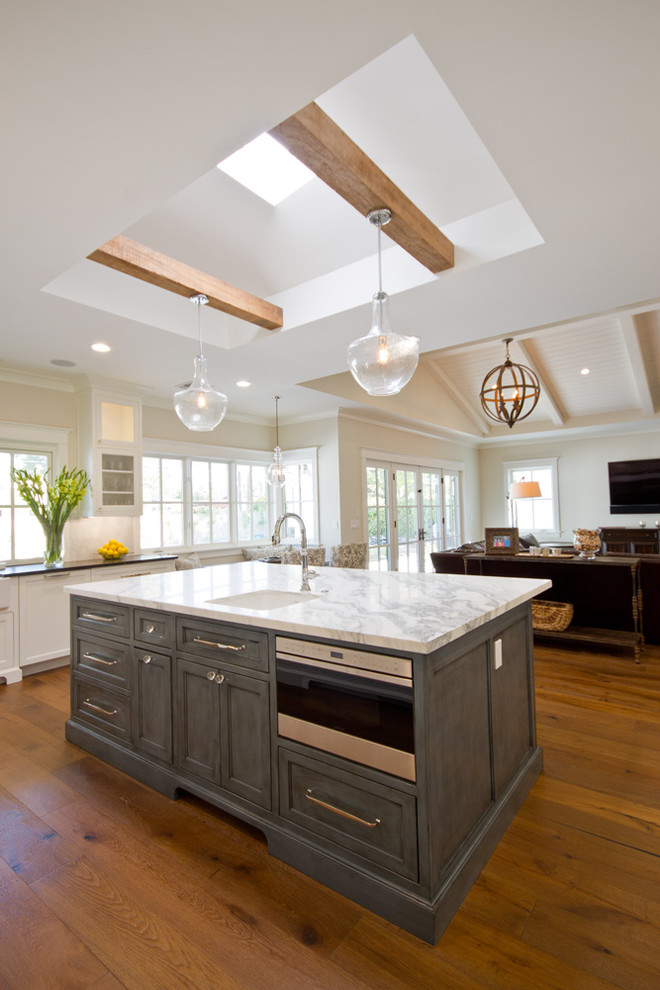 Inspiration for a large transitional u-shaped medium tone wood floor eat-in kitchen remodel in Phoenix with a farmhouse sink, recessed-panel cabinets, white cabinets, marble countertops, white backsplash, stone tile backsplash, stainless steel appliances and an island