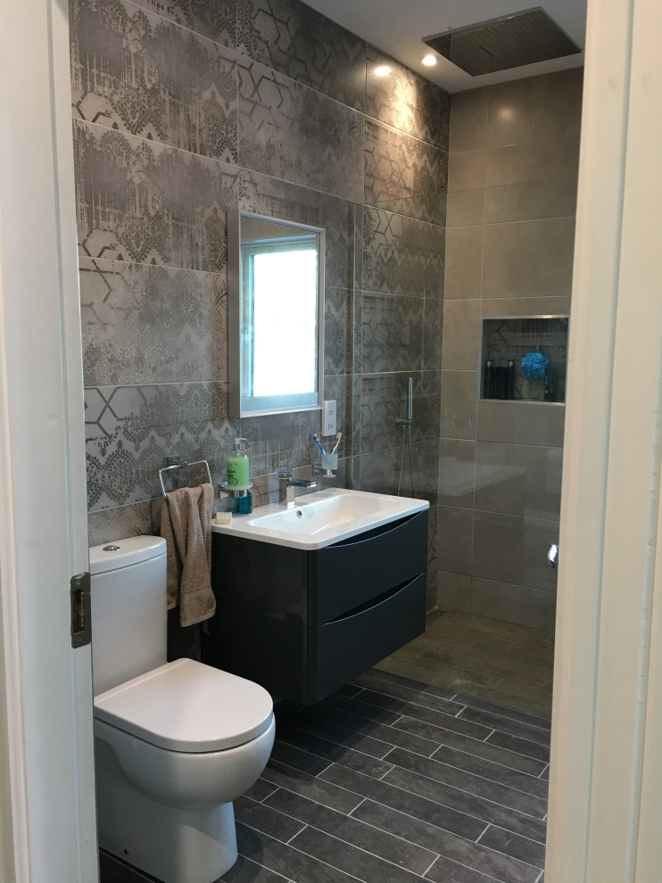 Example of a mid-sized trendy kids' ceramic tile, black floor and single-sink alcove bathtub design in Other with flat-panel cabinets, black cabinets, a two-piece toilet, gray walls, quartz countertops, beige countertops and a built-in vanity