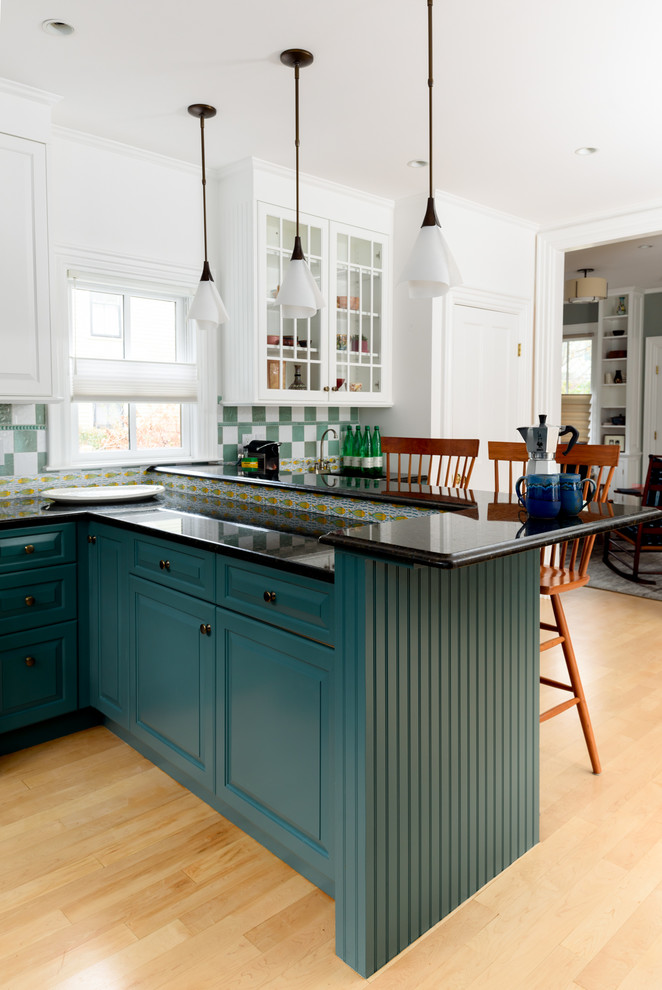 Design ideas for a large transitional u-shaped kitchen in Boston with raised-panel cabinets, green cabinets, granite benchtops, multi-coloured splashback, stainless steel appliances, light hardwood floors, a peninsula, black benchtop and ceramic splashback.