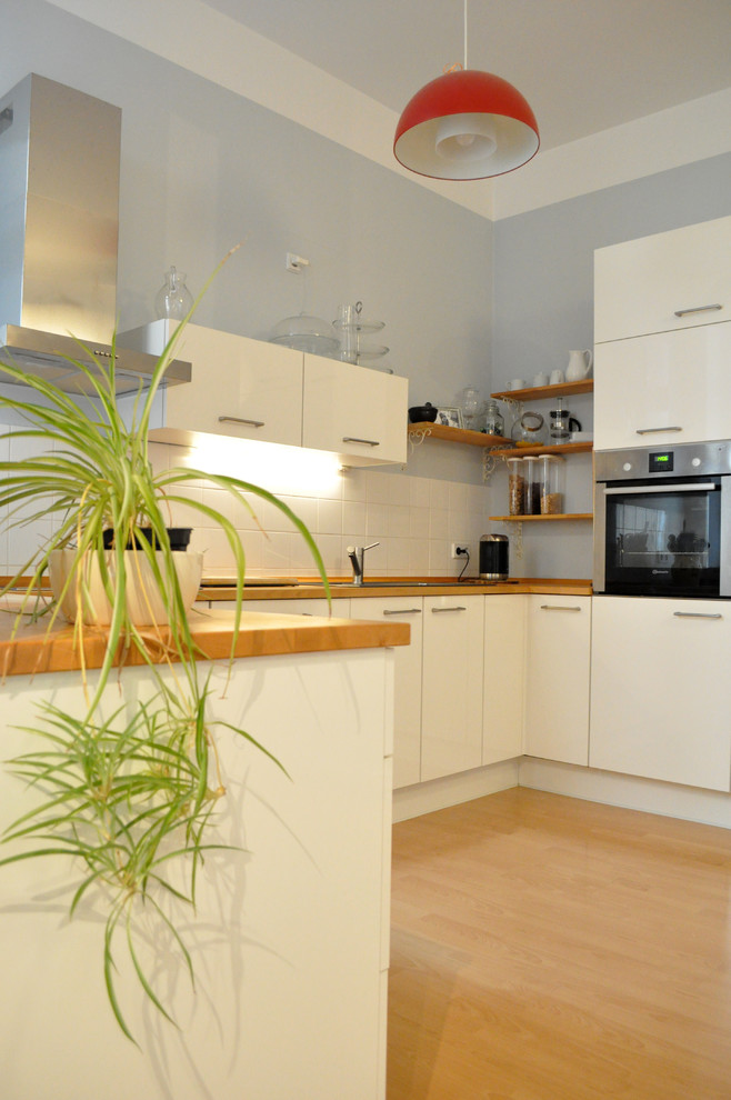 Immagine di una piccola cucina design con ante bianche, top in legno, paraspruzzi grigio, pavimento in laminato, nessuna isola e pavimento marrone