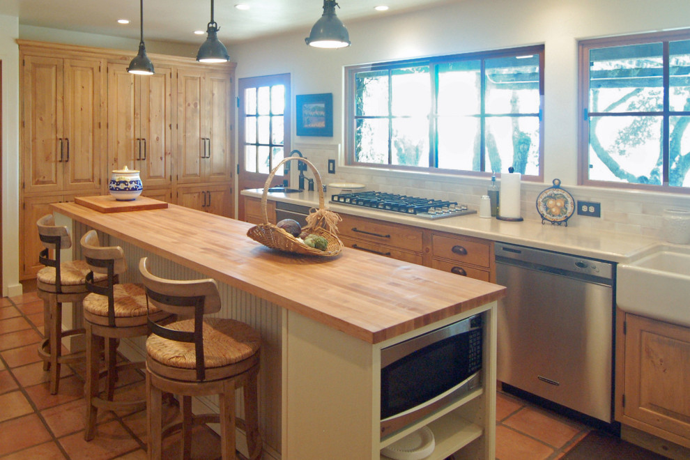 Design ideas for a large country l-shaped separate kitchen in San Luis Obispo with a farmhouse sink, raised-panel cabinets, light wood cabinets, white splashback, stone tile splashback, stainless steel appliances, terra-cotta floors, with island, white benchtop and limestone benchtops.