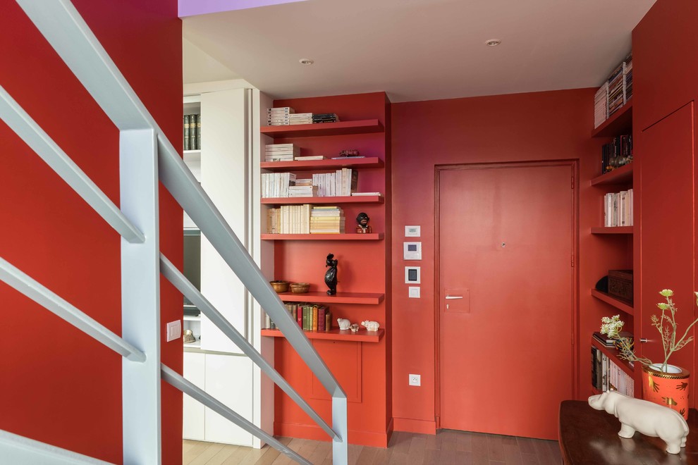 Design ideas for an expansive contemporary vestibule in Paris with orange walls, light hardwood floors, an orange front door and a single front door.
